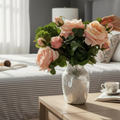 Bouquet of pink roses in a silver leaf stone vase on a  table in a bedroom.