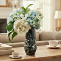BrookeLynn's Home Shadowed Swirl glass vase with a black and white marbled finish, holding blue and white floral stems.